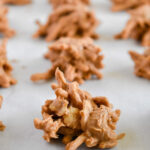 Close-up of clusters of crunchy, butterscotch haystacks on parchment paper, arranged in rows.