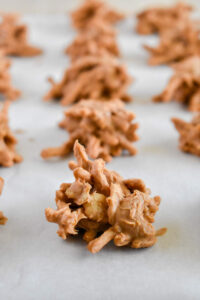 Close-up of clusters of crunchy, butterscotch haystacks on parchment paper, arranged in rows.