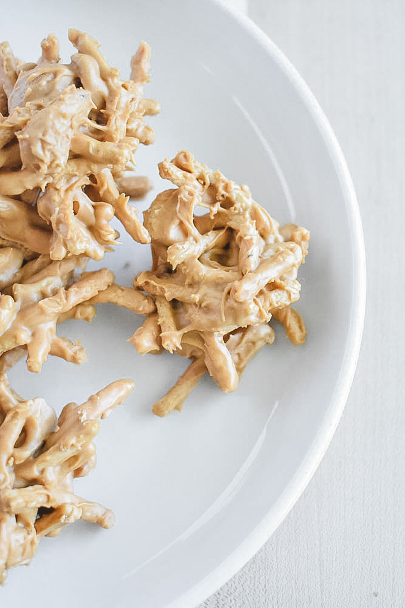 Butterscotch haystack clusters on a white plate, showing an irregular, golden-brown texture from the coated noodles.