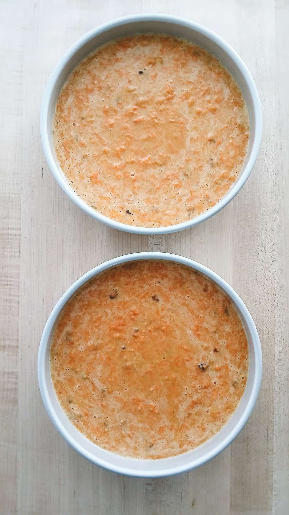 Carrot cake batter divided evenly into pans before baking.