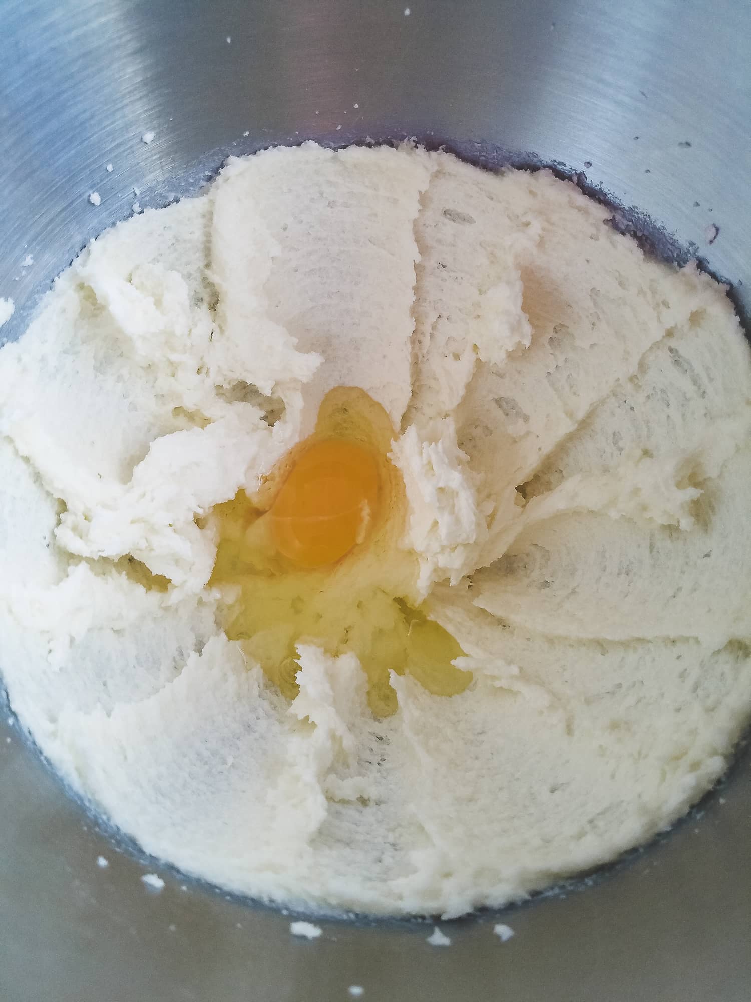 Adding a room temperature egg to creamed butter and sugar for soft cut out sugar cookies.