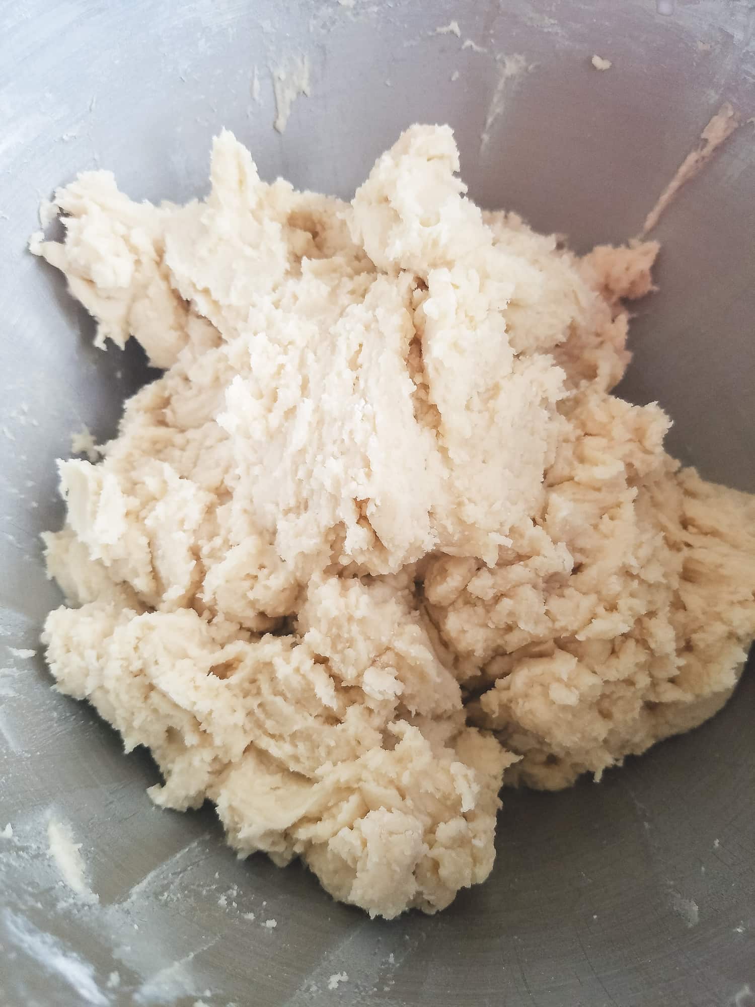 A mixing bowl filled with smooth, finished cut out sugar cookie dough that has passed the touch test.