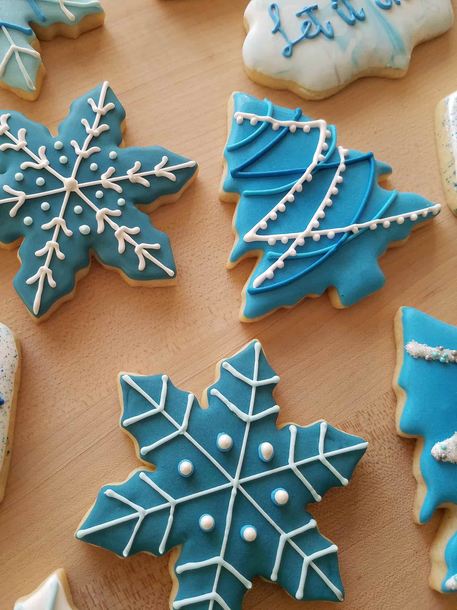 Winter-themed cut-out sugar cookies shaped like trees and snowflakes with blue and white royal icing.