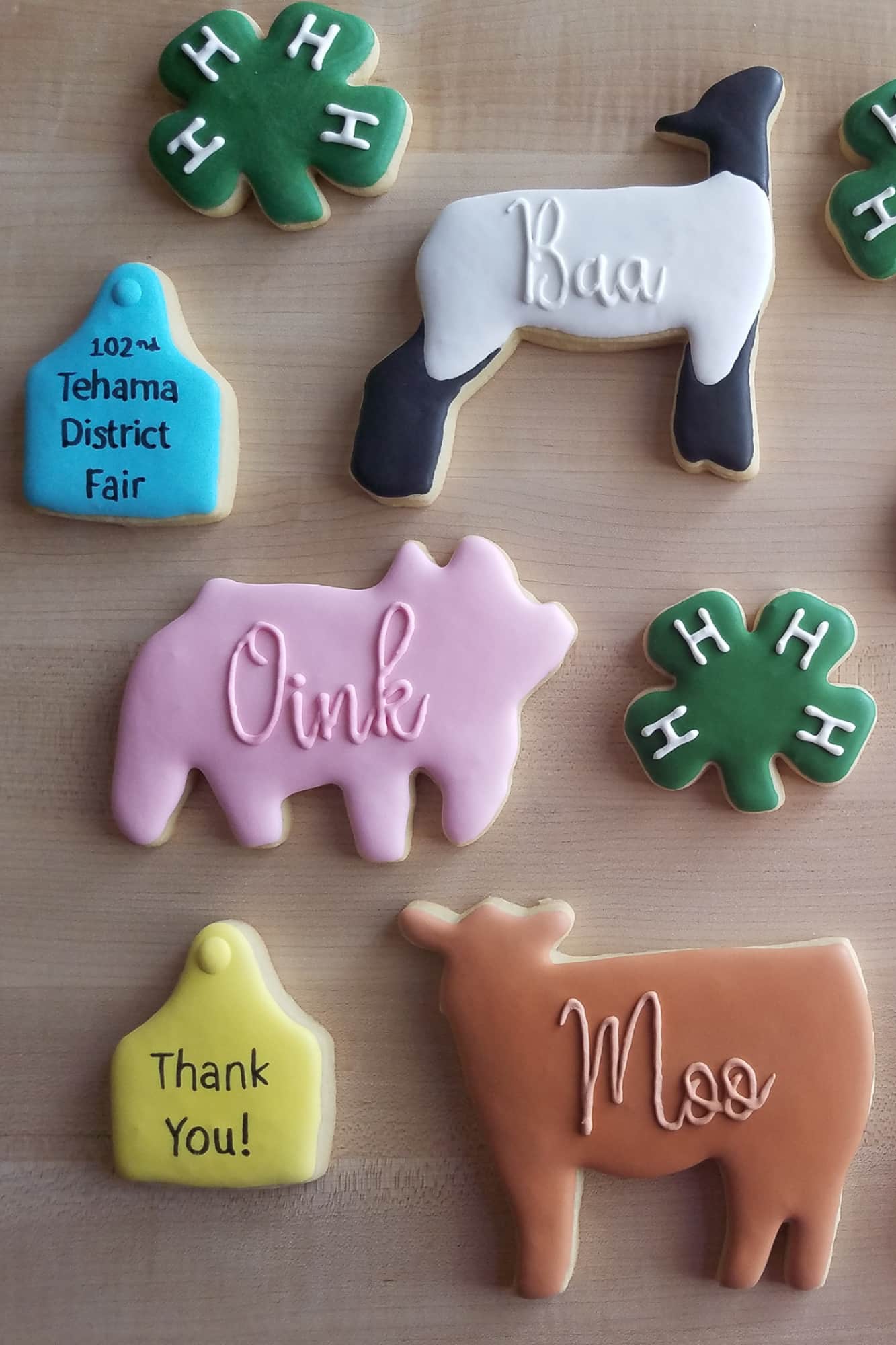 Assorted farm-themed cookies decorated with royal icing, including animal shapes with "Oink," "Baa," "Moo," green 4-H clovers, and fair-themed tags.