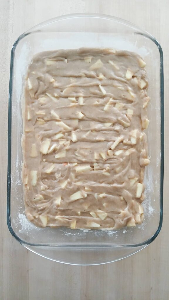 Apple cake batter in a glass baking dish before going into the oven
