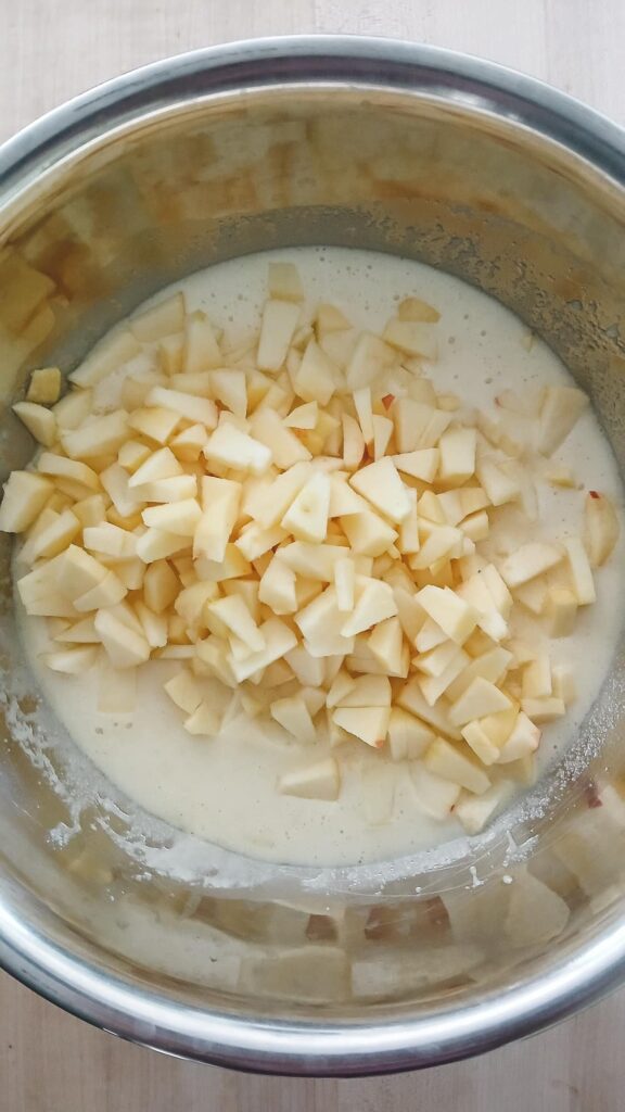 Diced apples added to the wet ingredients when making apple cake. The apples are ready to be mixed in