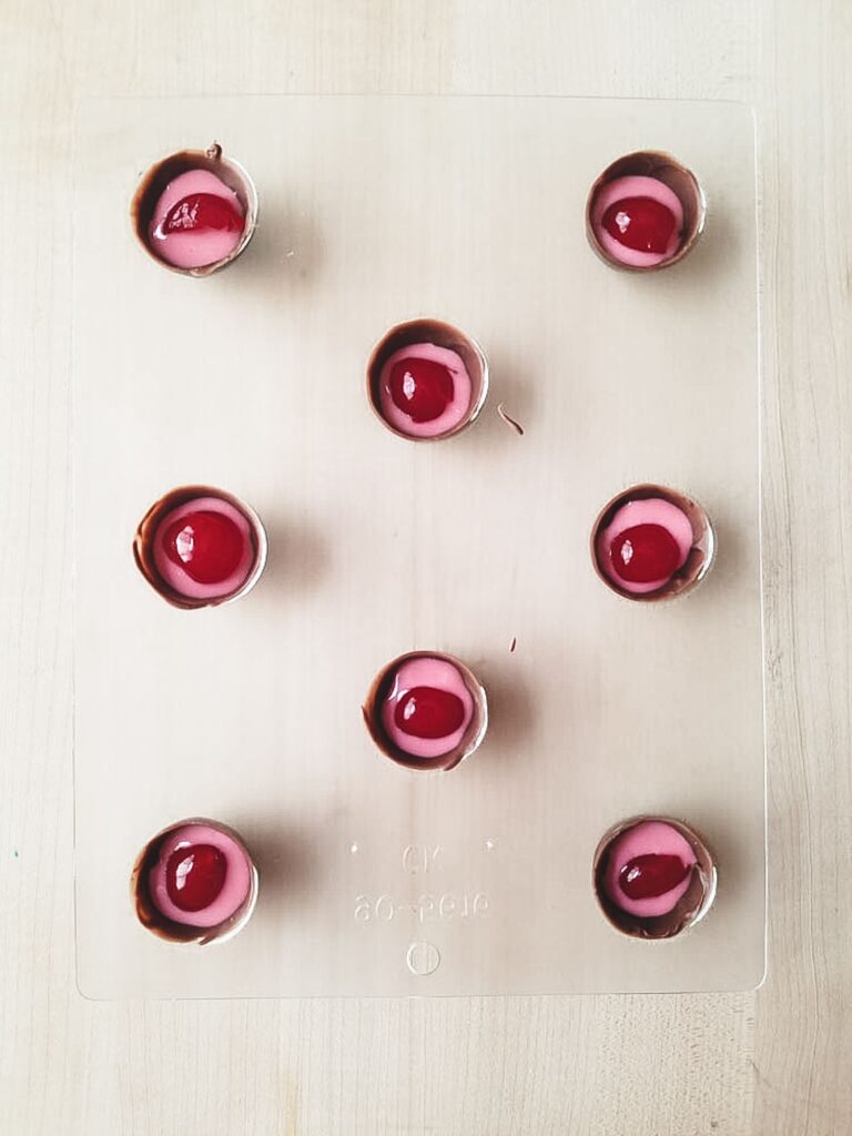 Chocolate covered cherry mold showing the chocolate shell, fondant, and cherry center ready to be topped with more chocolate