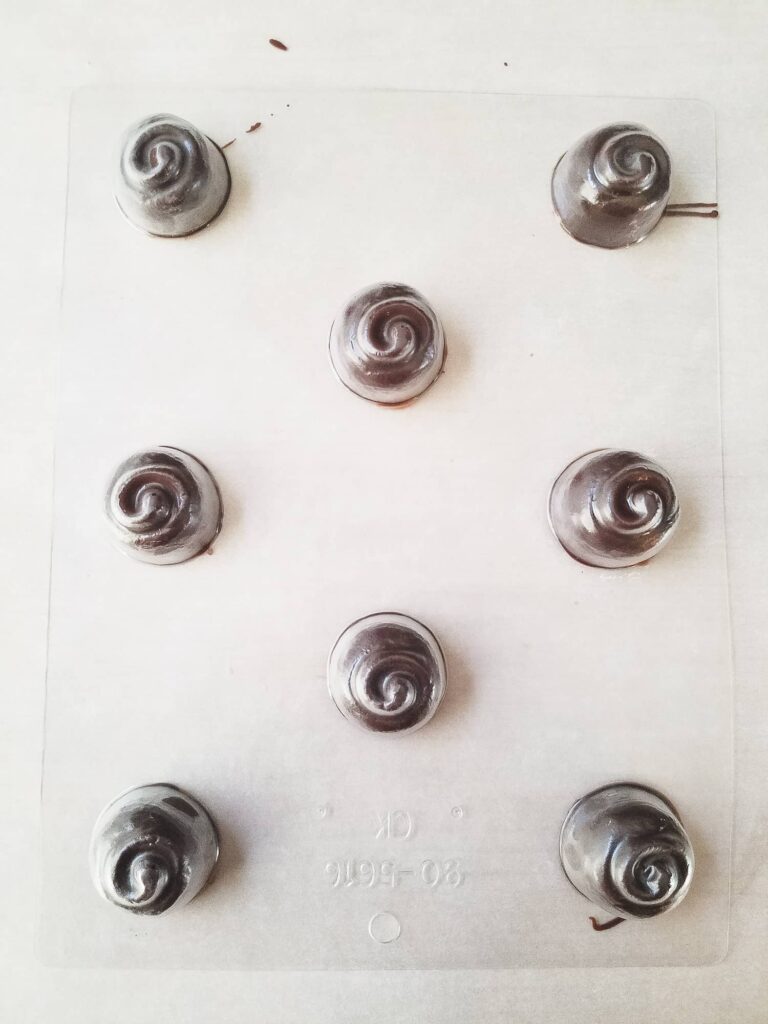 Chocolate covered cherries that are set and the candy mold is inverted to unmold the candy