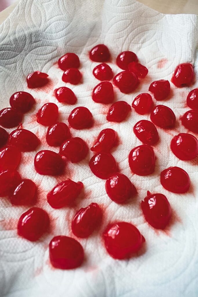 Bright red cherries cut in half are spread over a textured white paper towel