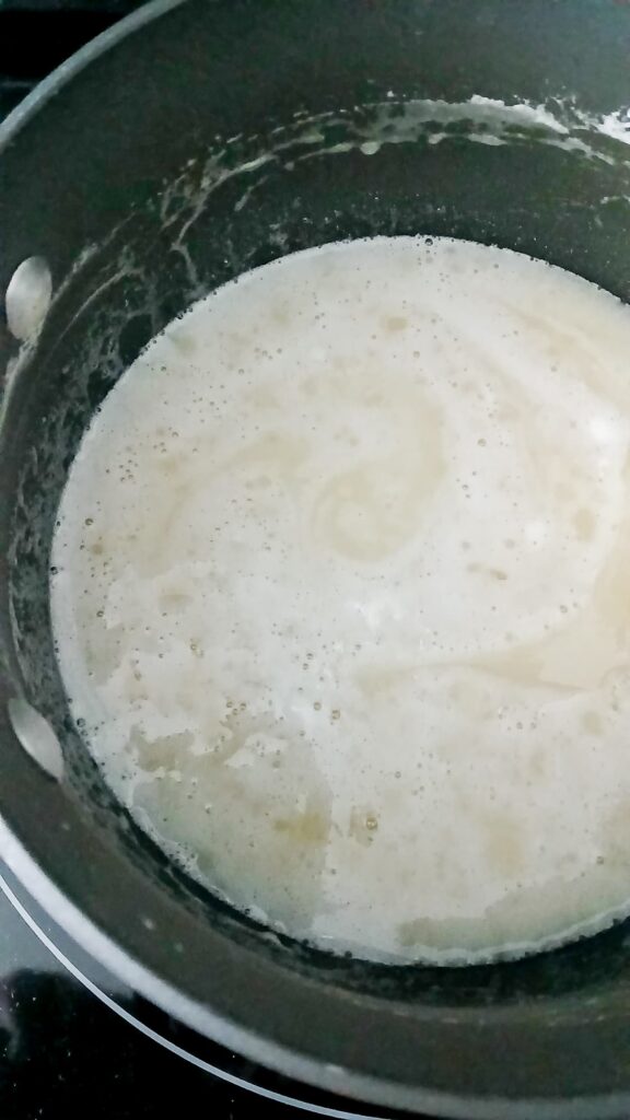Pot containing melted marshmallows, pineapple juice, and milk. The mixture looks frothy
