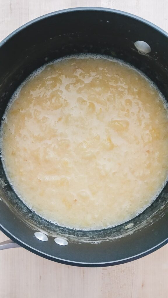 A pot with a yellow chunky texture that contains crushed pineapple and melted marshmallows