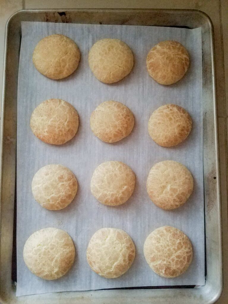 Freshly baked Snickerdoodles with crackled tops on a parchment-lined baking pan