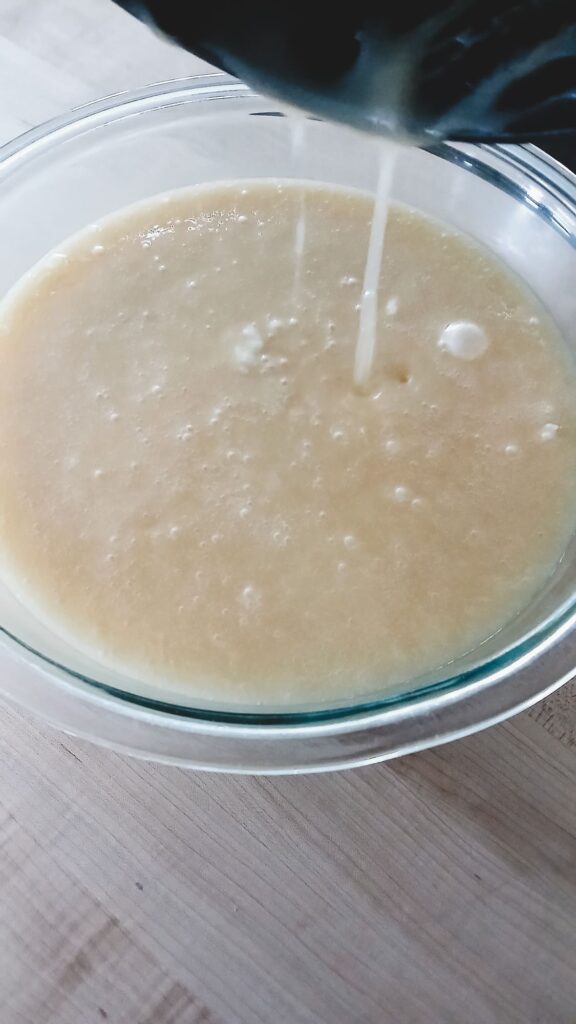 Hot sugar mixture completely covering the marshmallow fluff and chocolate chips in a glass bowl, ready to be stirred into a smooth chocolate fudge