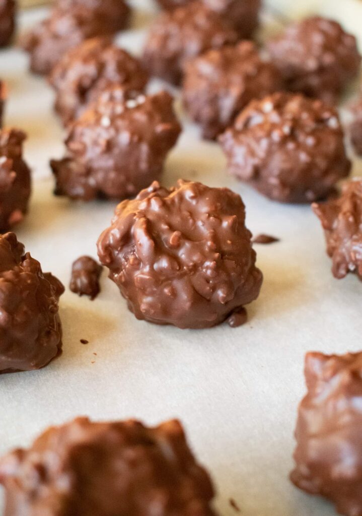 Close-up of several homemade cherry mash candies on parchment paper, showcasing a rough texture and glossy finish