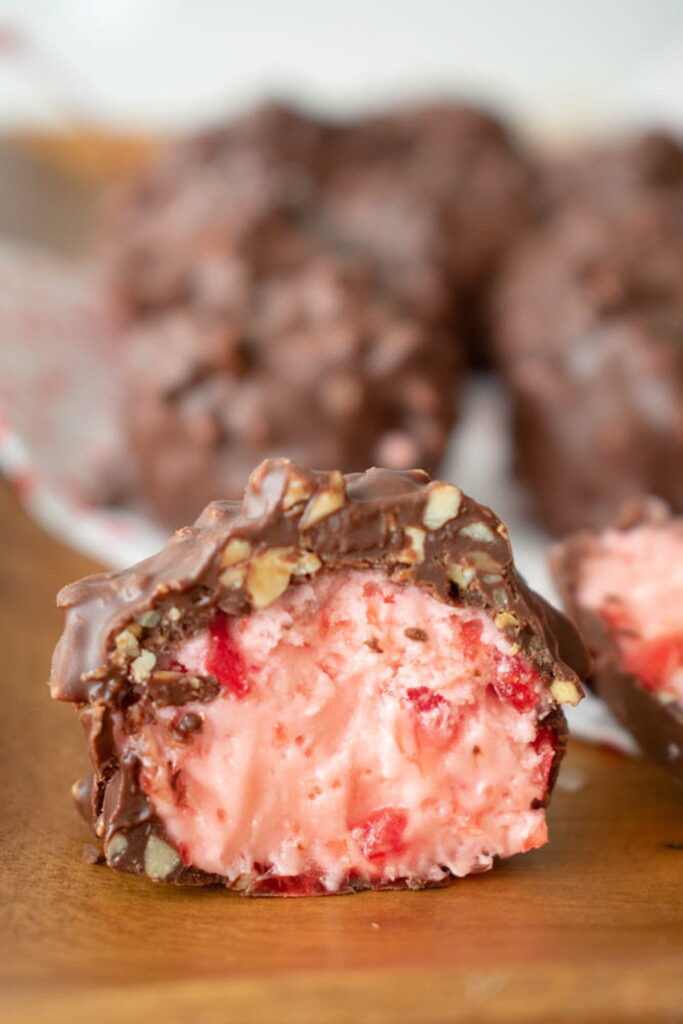 Close-up of cherry mash candy cut in half, revealing a creamy pink center with red cherry bits.
