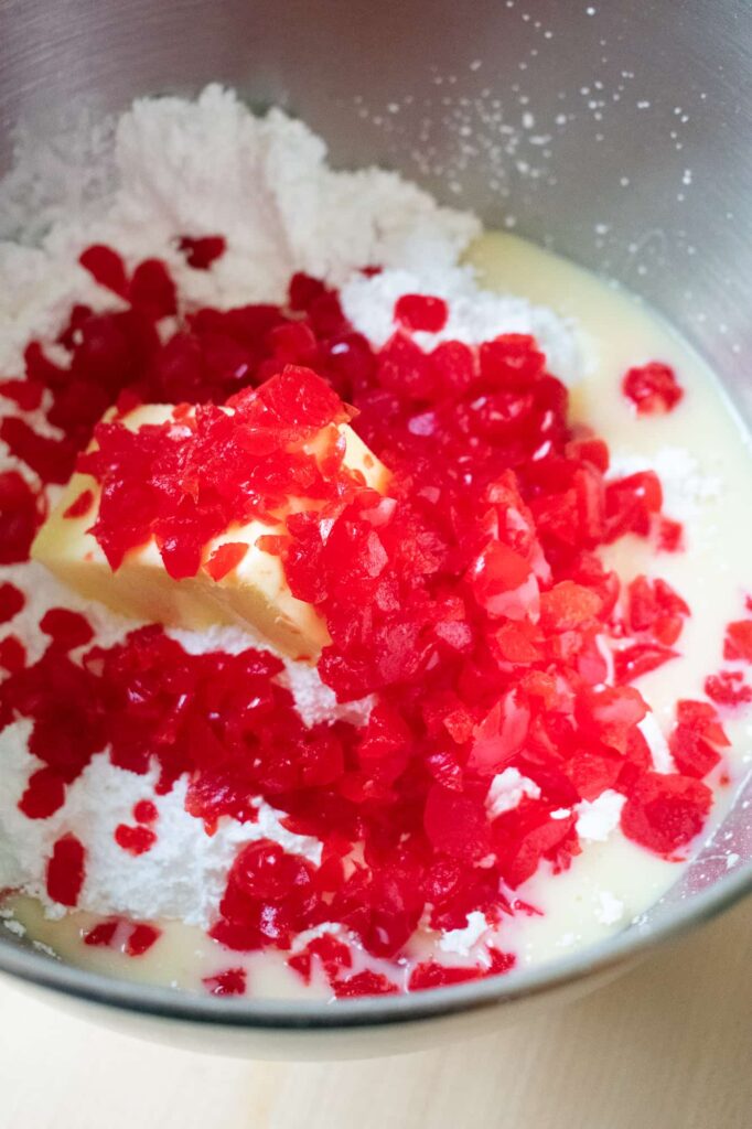 Mixing bowl with chopped bright red cherries, butter, and sugar ready to make the filling for cherry mash candy