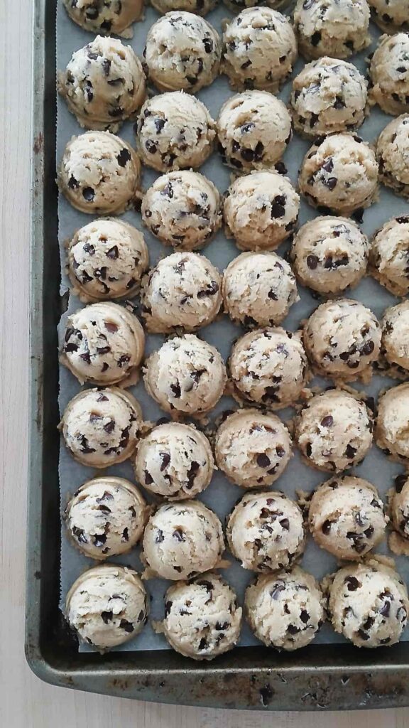 A baking sheet of portioned chocolate chip cookie dough balls ready for the refrigerator.