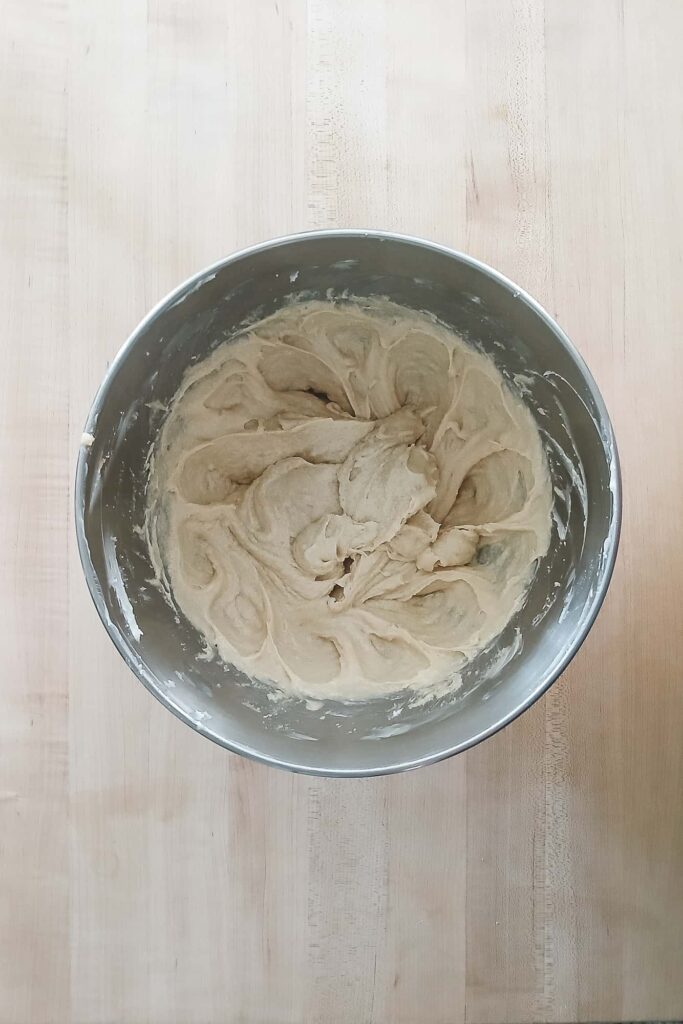 A smooth and creamy cookie dough emulsion after mixing in the eggs, showing a glossy, uniform texture with no streaks of fat.