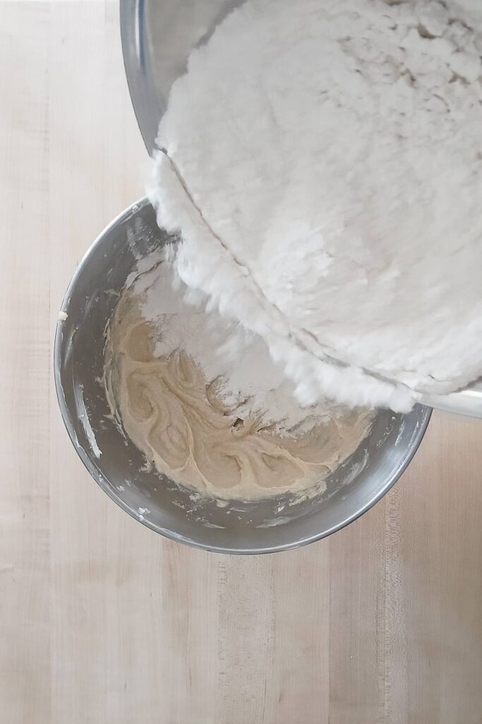 Adding the first portion of the flour mixture to the cookie dough base