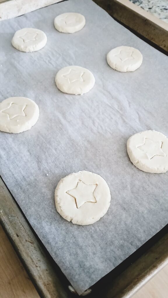Frozen whipped shortbread cookie dough spaced two inches apart on a parchment-lined baking tray and ready to bake.
